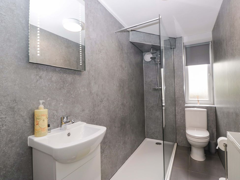 A bathroom with a shower, sink, and toilet at Courtyard Cottage, Cartmel