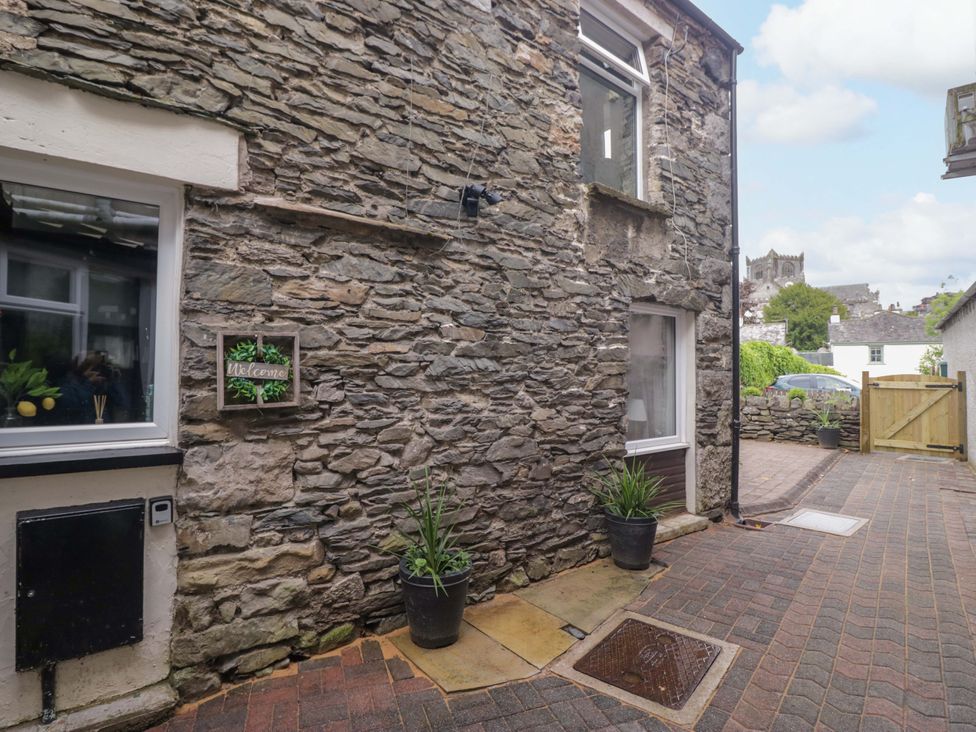 An outdoor area with a stone wall and plants at Courtyard Cottage in Cartmel