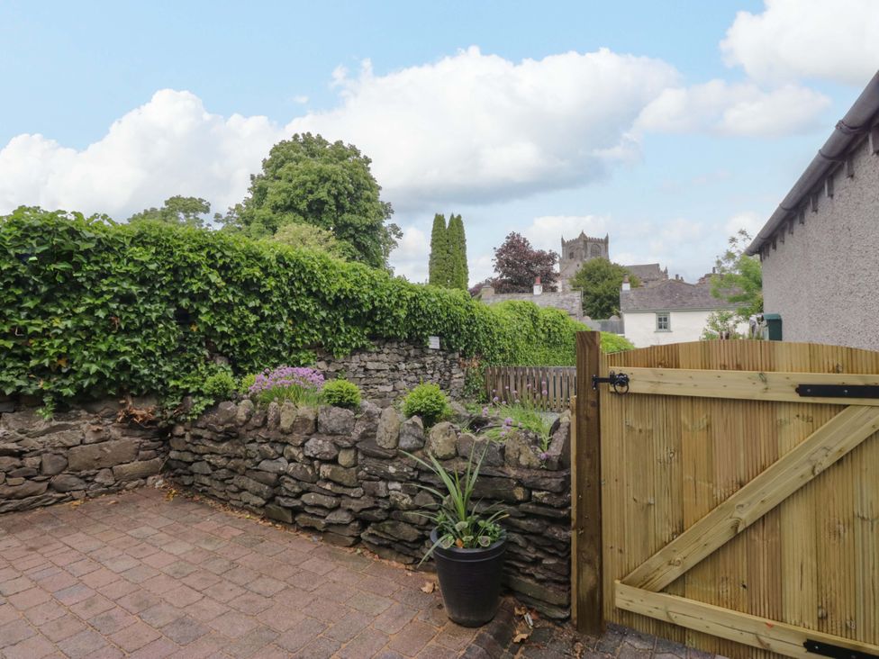 An outdoor garden with a stone wall and gate at Courtyard Cottage in Cartmel