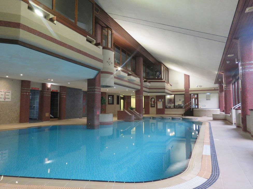 An indoor pool with seating and stairs at Courtyard Cottage in Cartmel