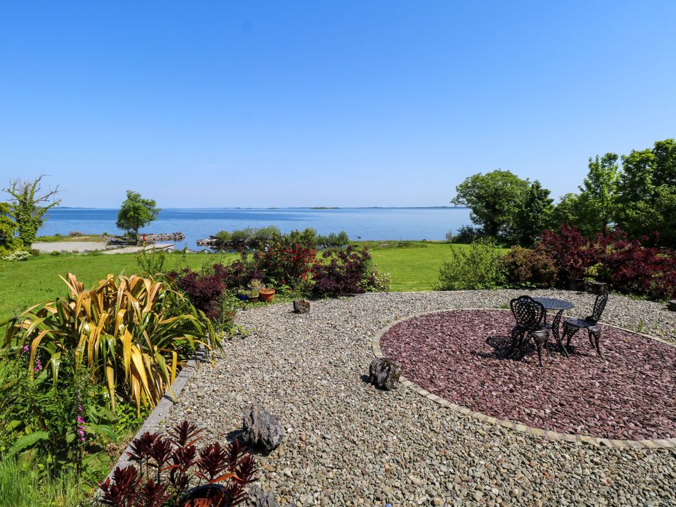 A garden with a table and chairs overlooking the water at Mayfly Cottage
