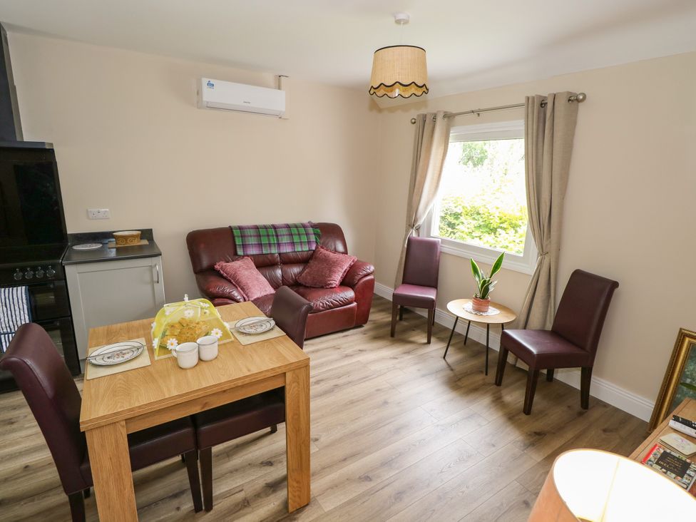 A living room with a sofa and dining table at Mayfly Cottage