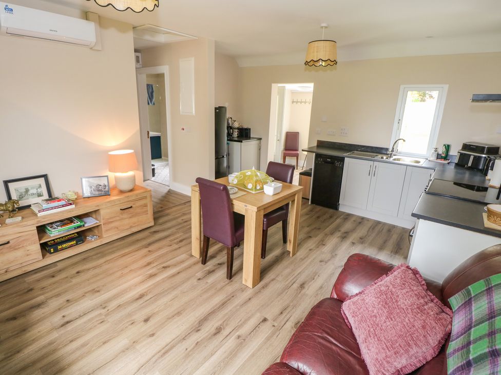 A living room and kitchen area with furniture at Mayfly Cottage