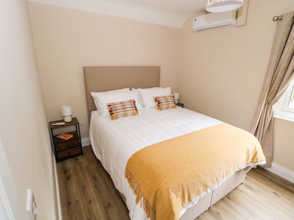 A bedroom with a bed and nightstand at Mayfly Cottage