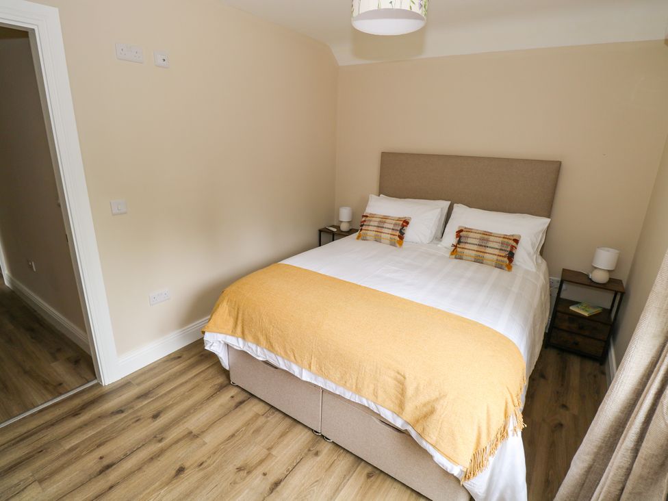 A bedroom with a bed and nightstand at Mayfly Cottage