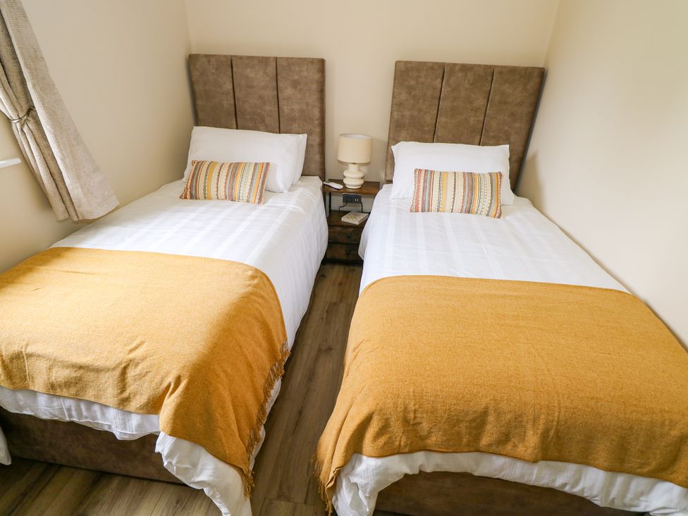 A bedroom with two single beds and a lamp at Mayfly Cottage
