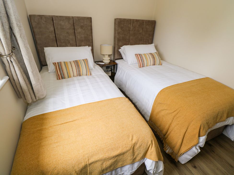 A bedroom with two single beds at Mayfly Cottage