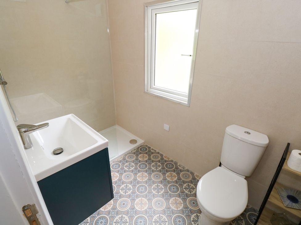 A bathroom featuring a shower, toilet, and washbasin at Mayfly Cottage