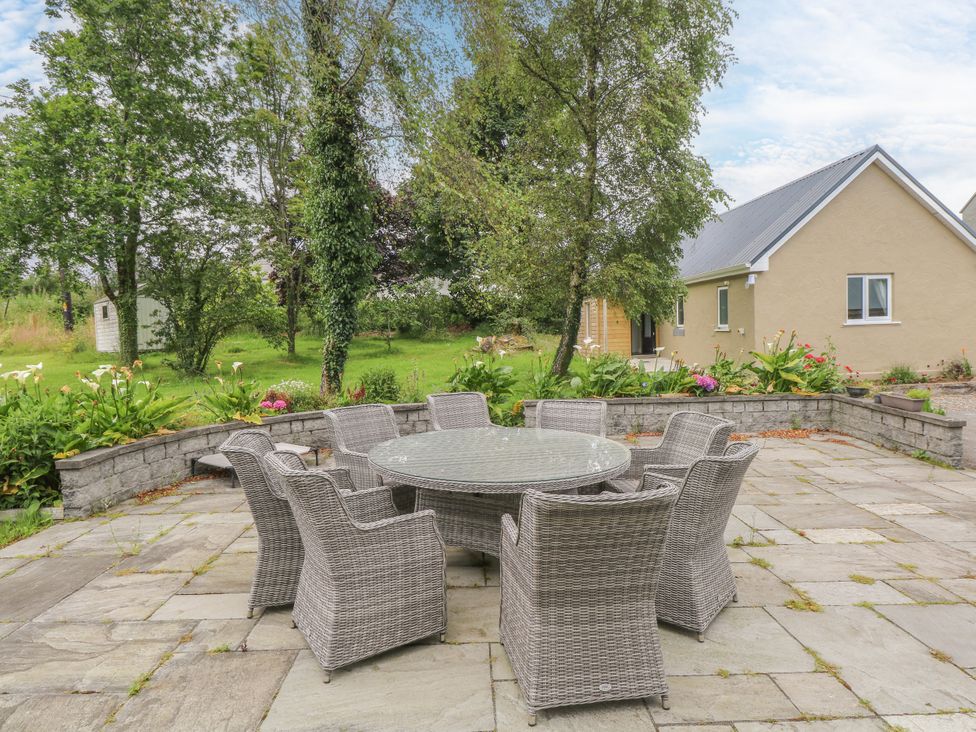 An outdoor patio with a circular table and chairs at Mayfly Cottage