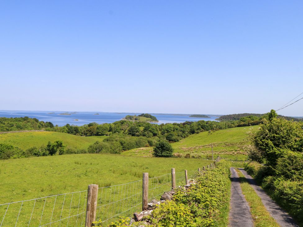 A view of a grassy landscape with a road and water at Mayfly Cottage