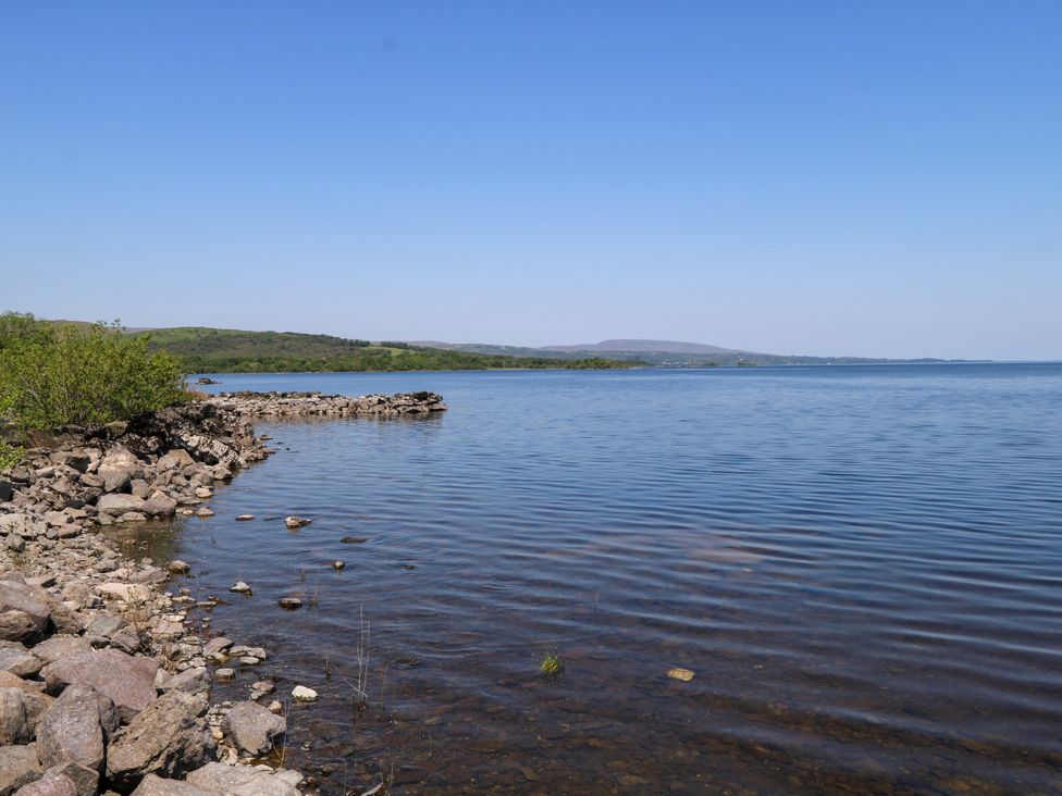A shoreline with rocks and water at Mayfly Cottage