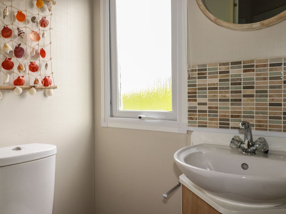 A bathroom with a sink, toilet, and window at Tucked Away in Newquay