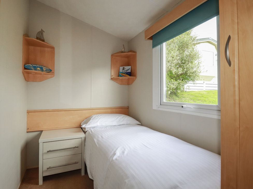 A bedroom with a bed and shelves at Tucked Away in Newquay