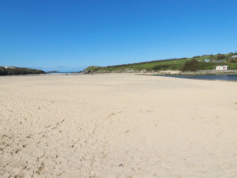 A beach with sand and water at Tucked Away in Newquay