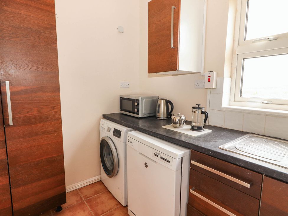 A kitchen with appliances including a washing machine and a microwave at Golf Club View, County Clare