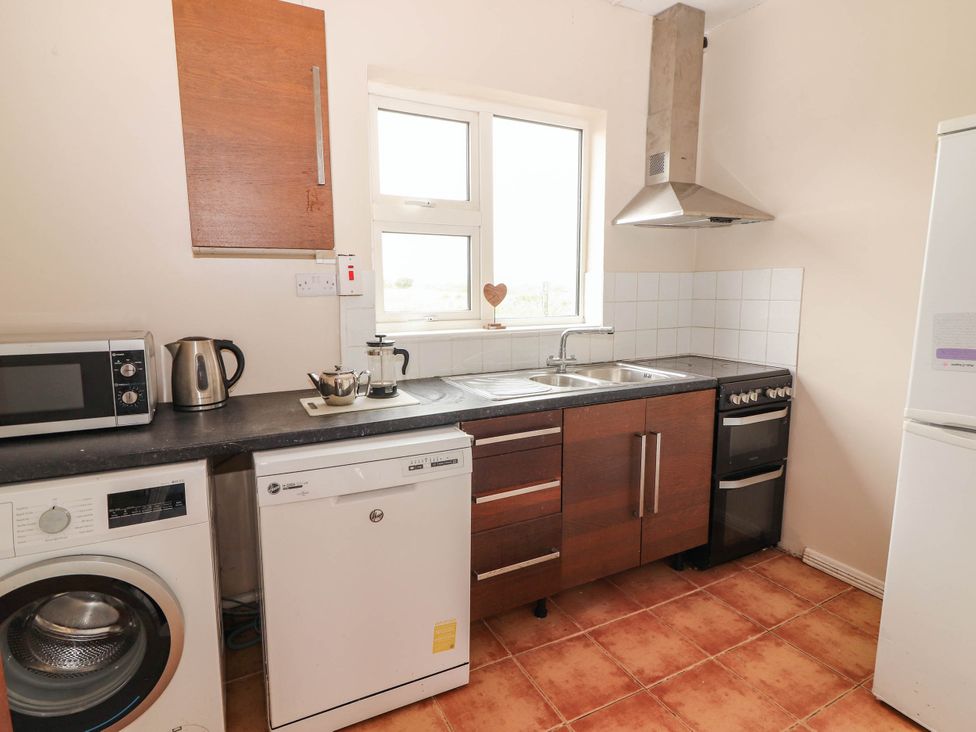 A kitchen with a washing machine, dishwasher, and microwave at Golf Club View in County Clare