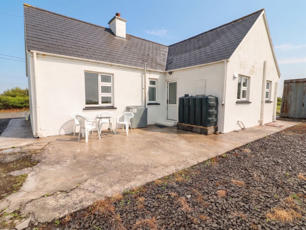 An outdoor area with a house, table, and chairs at Golf Club View, County Clare