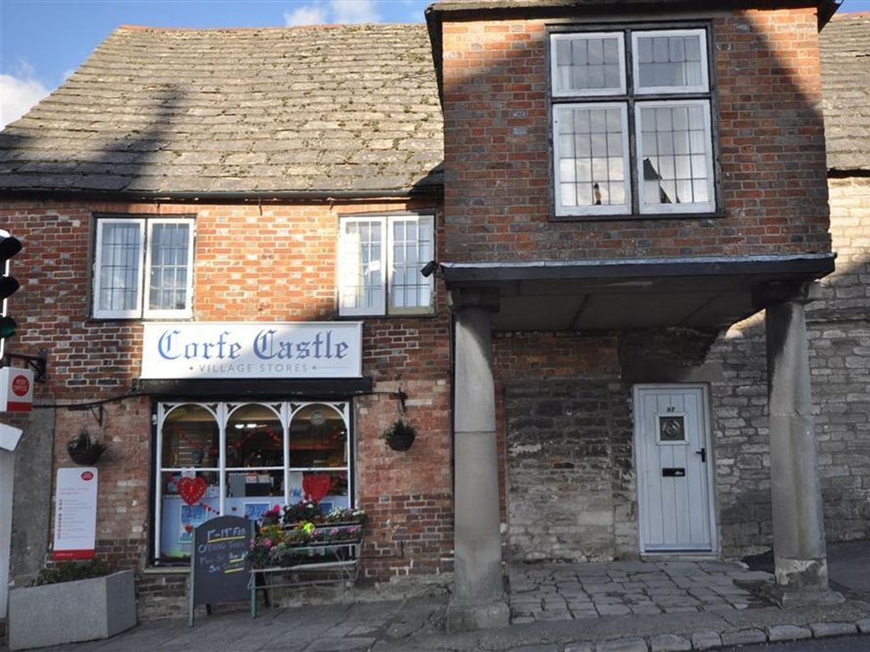 A storefront of Corfe Castle Village Stores with a sign and columns in Wareham