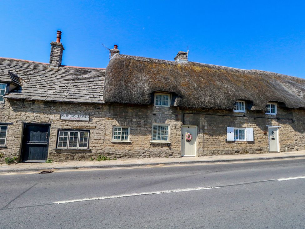 A thatched cottage with stone walls and front door at Little Wickers in Corfe Castle