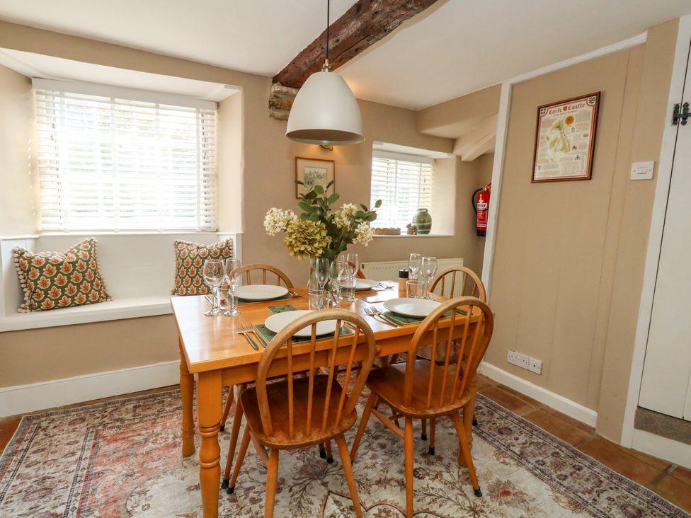 A dining room with a table set for meals at Little Wickers in Corfe Castle