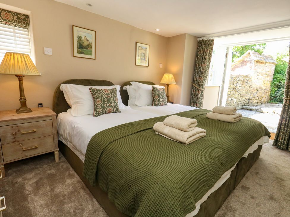 A bedroom with two beds and a bedside table at Little Wickers in Corfe Castle