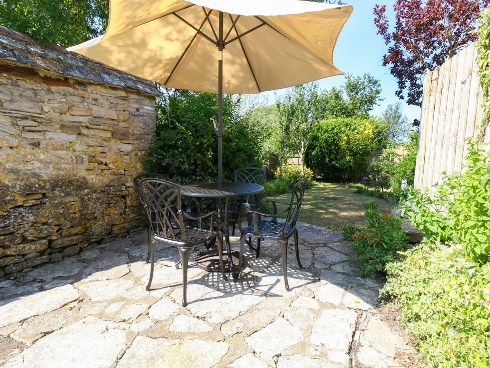 A garden with a table and chairs under an umbrella at Little Wickers Corfe Castle
