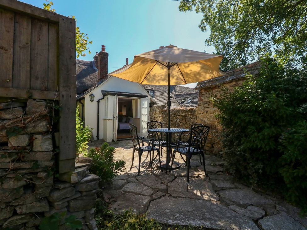 A garden with a table and chairs under an umbrella at Little Wickers in Corfe Castle