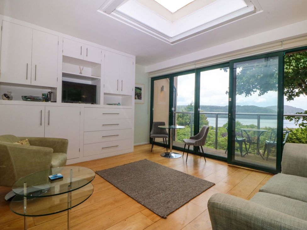 A living room with furniture and sliding glass doors at The Treehouse in Colwyn Bay