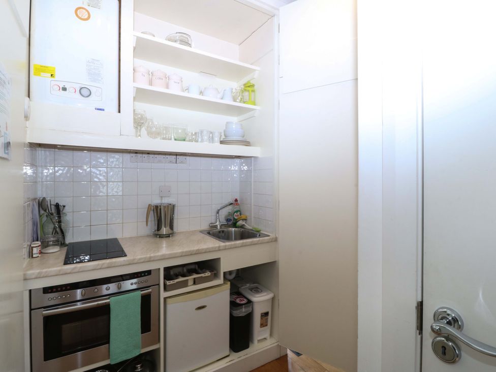 A kitchen with a sink, stove and storage at The Treehouse in Colwyn Bay