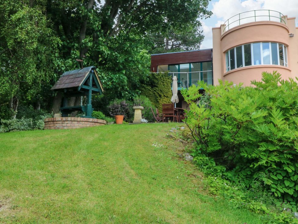 A garden with a well and potted plants at The Treehouse in Colwyn Bay
