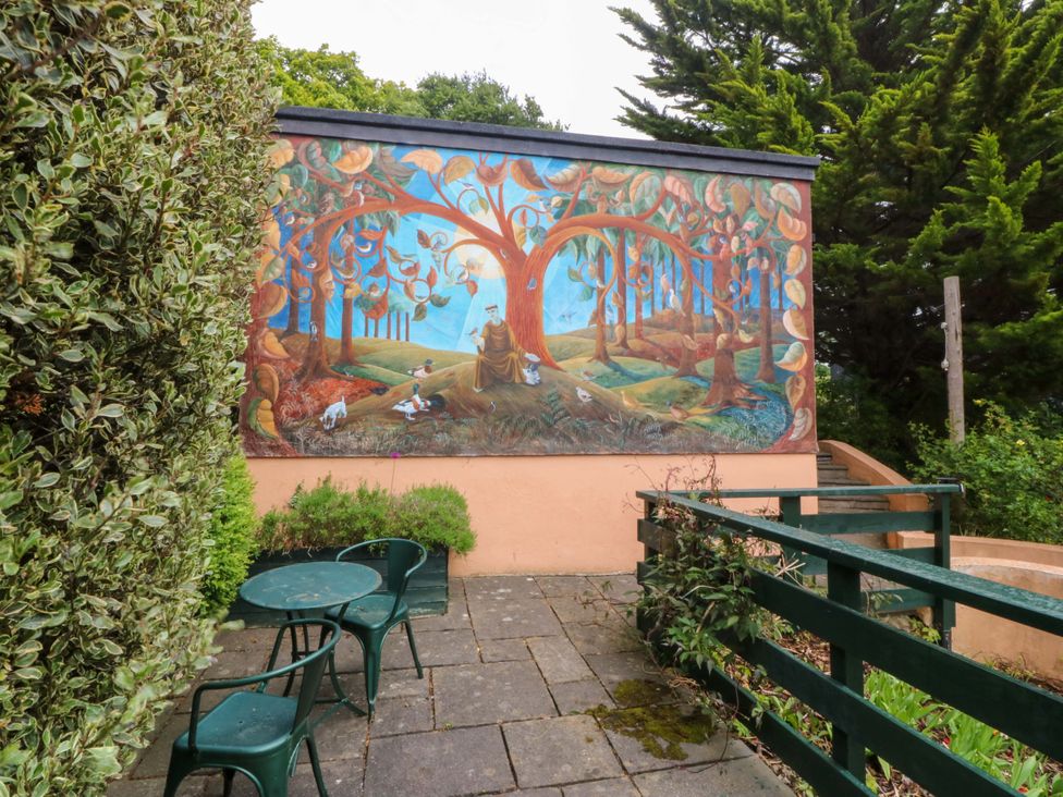 An outdoor area with a mural on a wall and a table with chairs at The Treehouse in Colwyn Bay