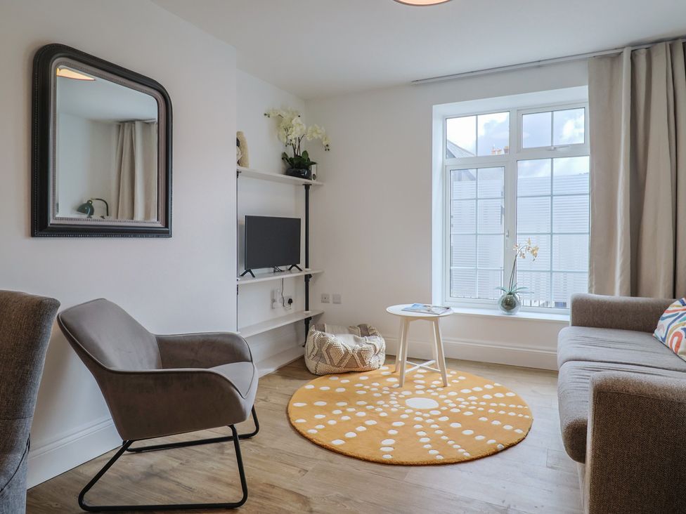 A living room with a mirror, sofa, and television at Flat 1 Harley House in Sidmouth