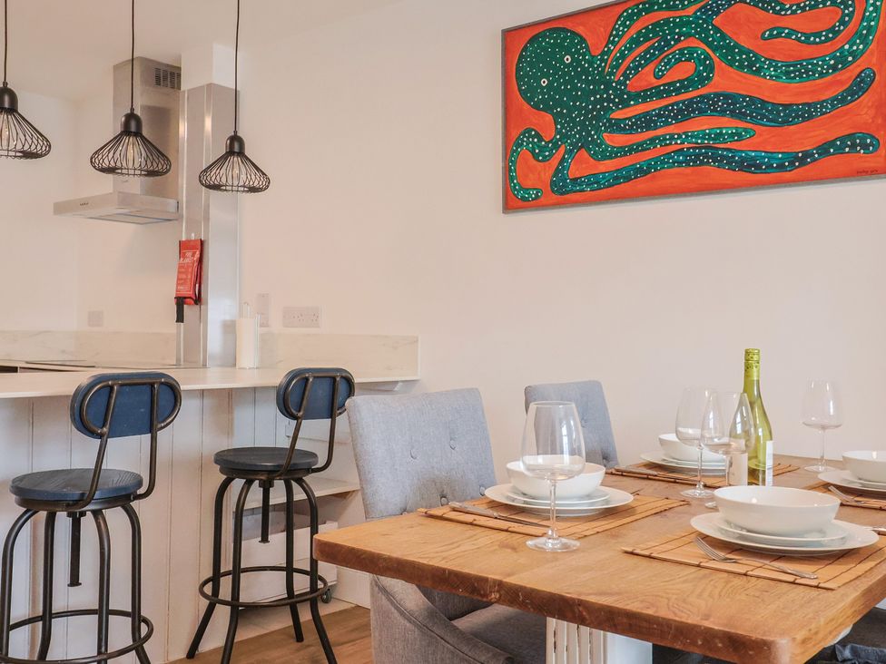 A dining room with a wooden table and kitchen counter at Flat 1 Harley House in Sidmouth