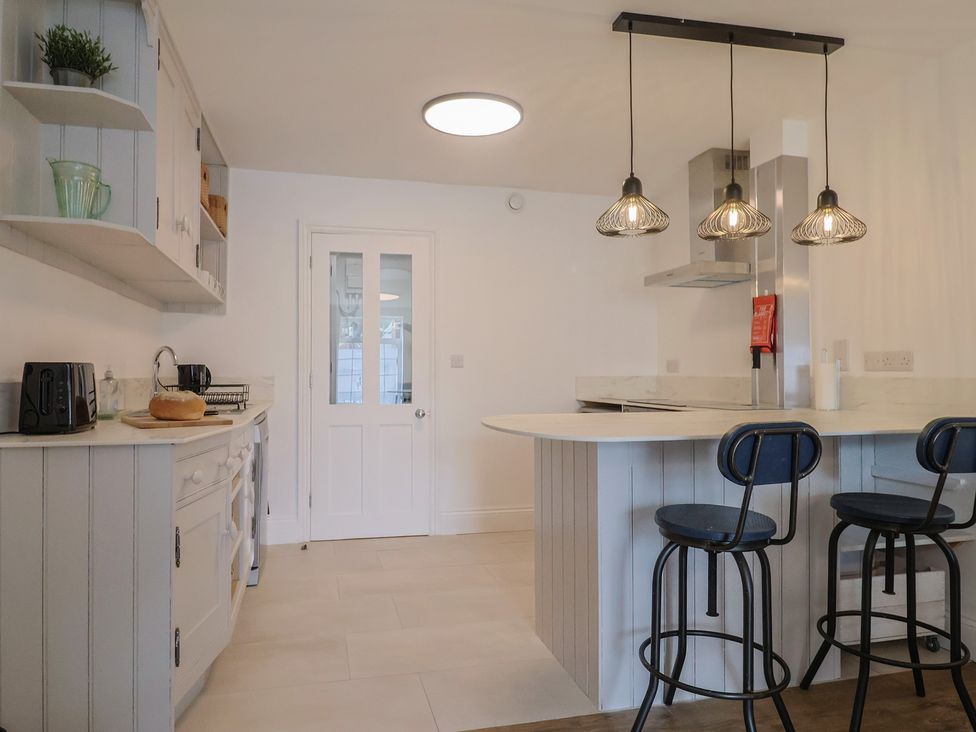 A kitchen with appliances and seating area at Flat 1 Harley House in Sidmouth