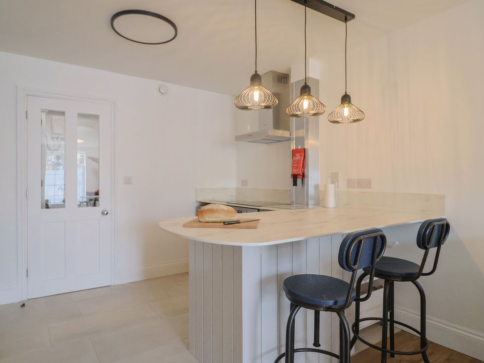 A kitchen with a bar area and stools at Flat 1 Harley House Sidmouth