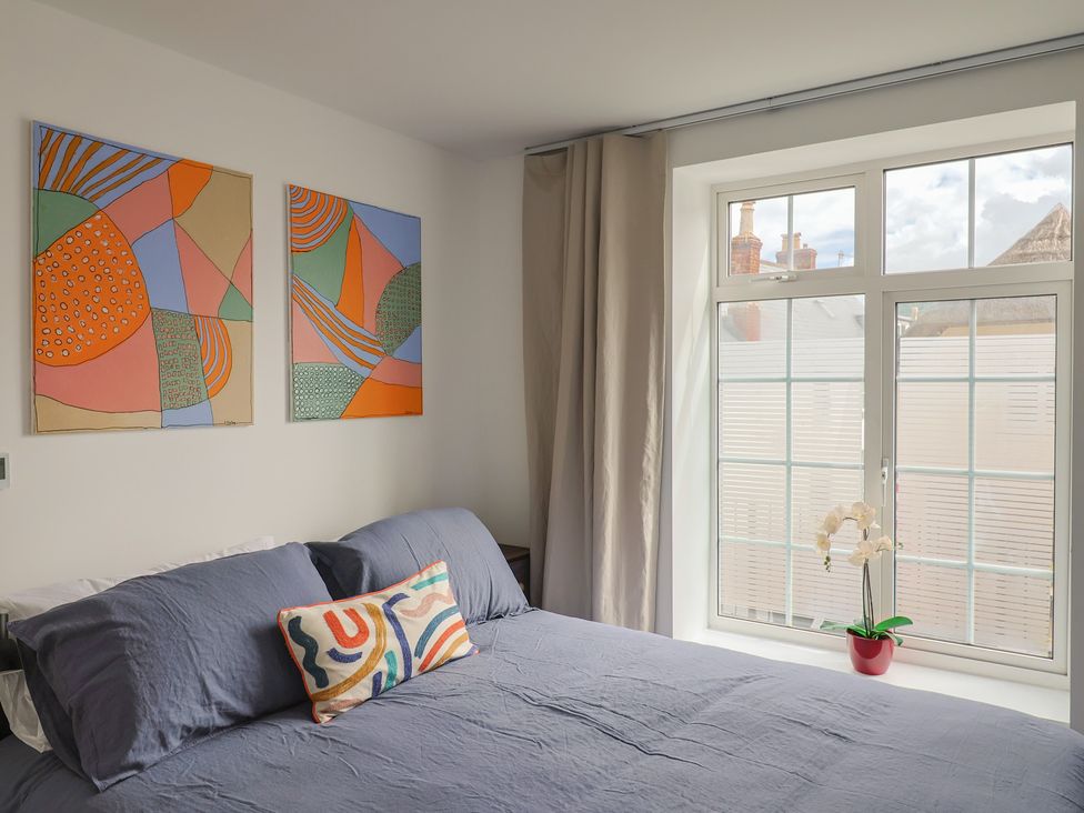 A bedroom with a bed and paintings on the wall at Flat 1 Harley House Sidmouth