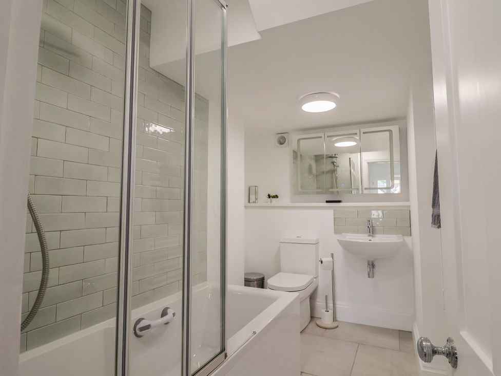 A bathroom with a shower, bathtub, toilet and sink at Flat 1 Harley House, Sidmouth