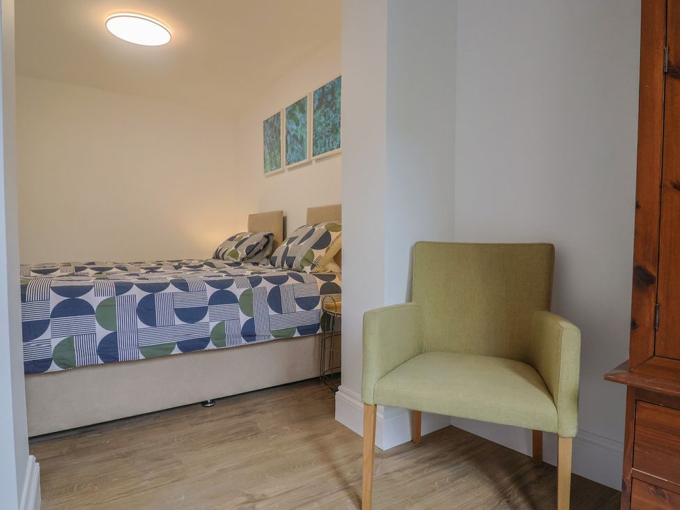 A bedroom with a bed and a chair at Flat 1 Harley House in Sidmouth