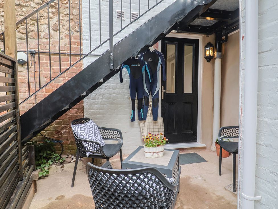 An outdoor patio with wetsuits hanging by the door at Flat 1 Harley House, Sidmouth