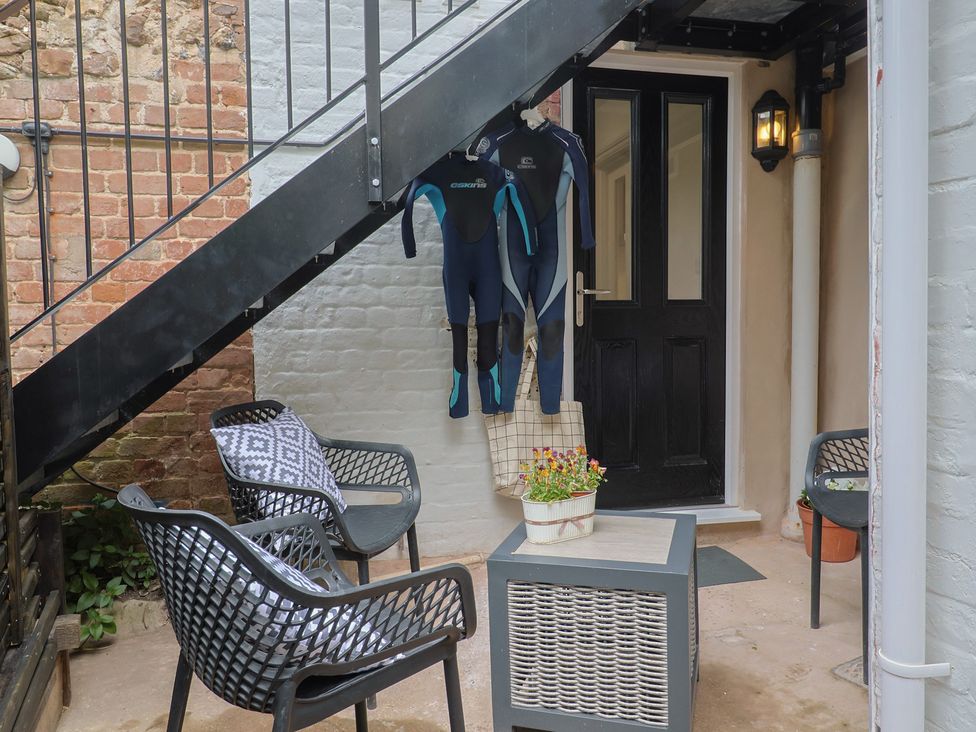 An outdoor area with a door, wetsuits hanging and seating at Flat 1 Harley House Sidmouth