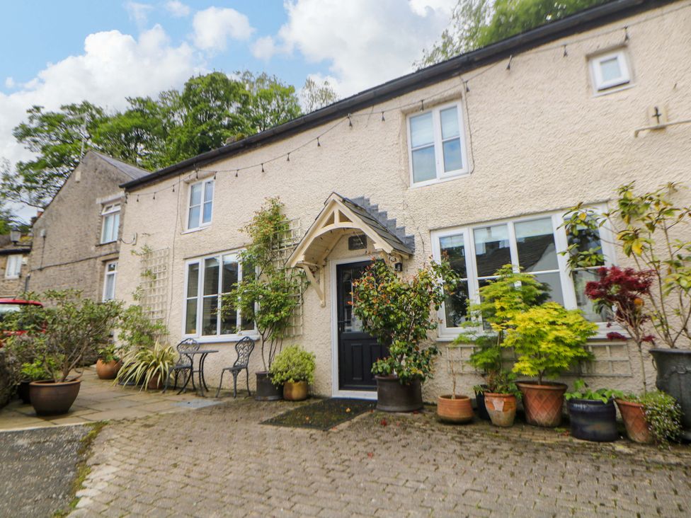 An exterior view of a house with plants and chairs at Bargate Cottage in Hope Valley
