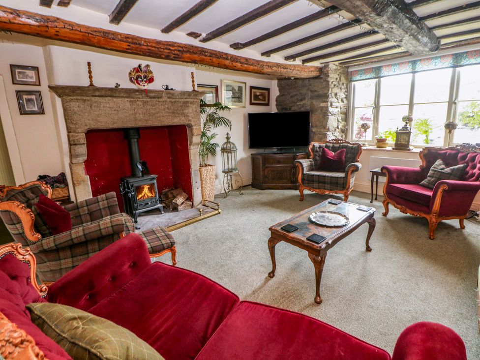 A living room with a fireplace and television at Bargate Cottage in Hope Valley