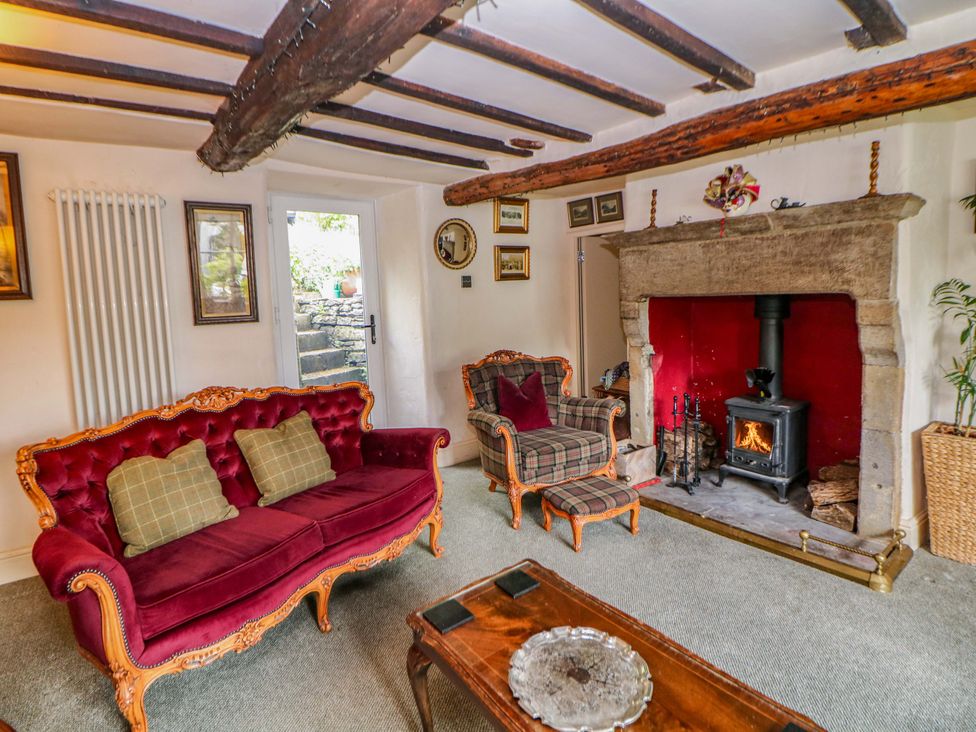 A living room with a fireplace and seating area at Bargate Cottage in Hope Valley