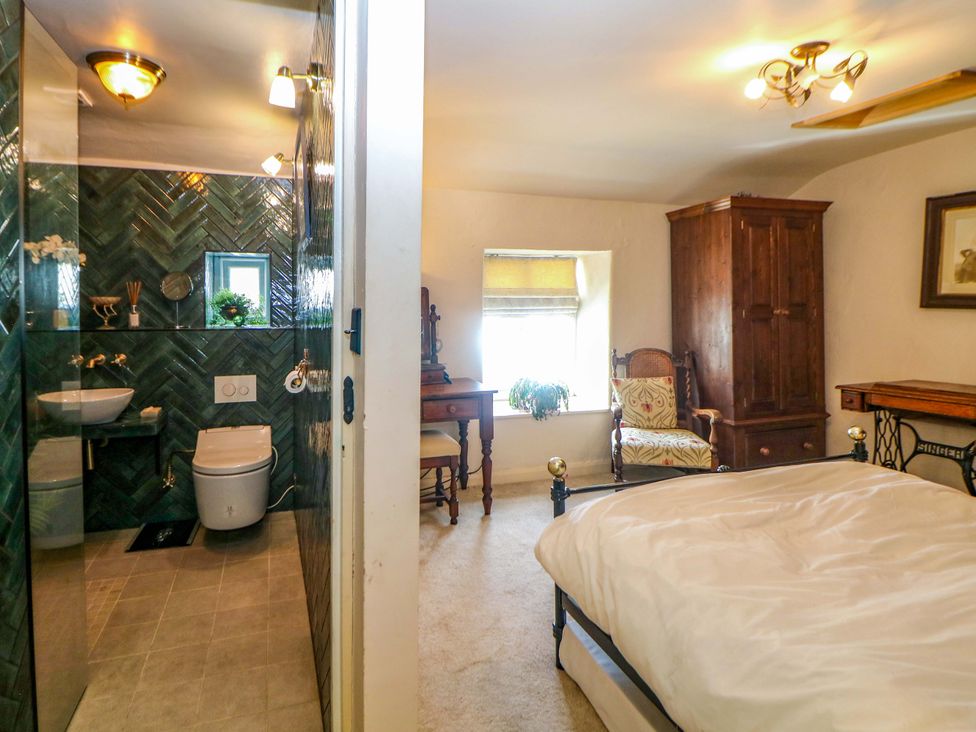 A bathroom with a sink and shower adjacent to a bedroom at Bargate Cottage in Hope Valley