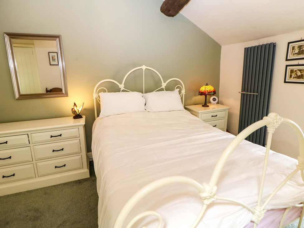 A bedroom with a bed and dresser at Bargate Cottage in Hope Valley