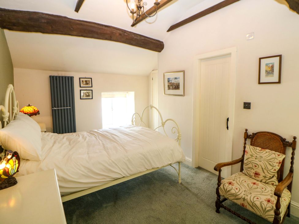A bedroom with a bed and chair at Bargate Cottage in Hope Valley