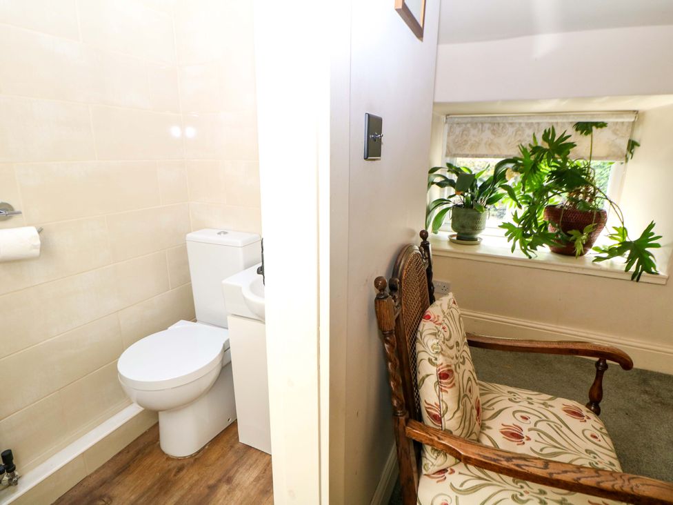 A bathroom with a toilet and sink plus a chair at Bargate Cottage in Hope Valley