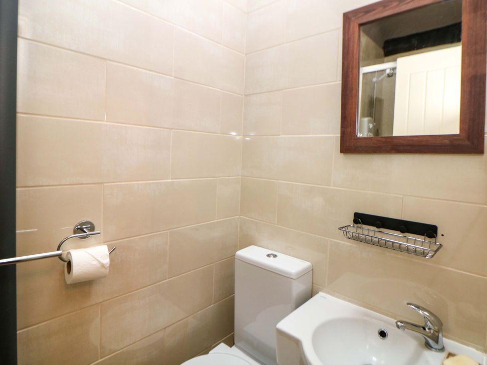 A bathroom with a toilet, sink, and mirror at Bargate Cottage Hope Valley
