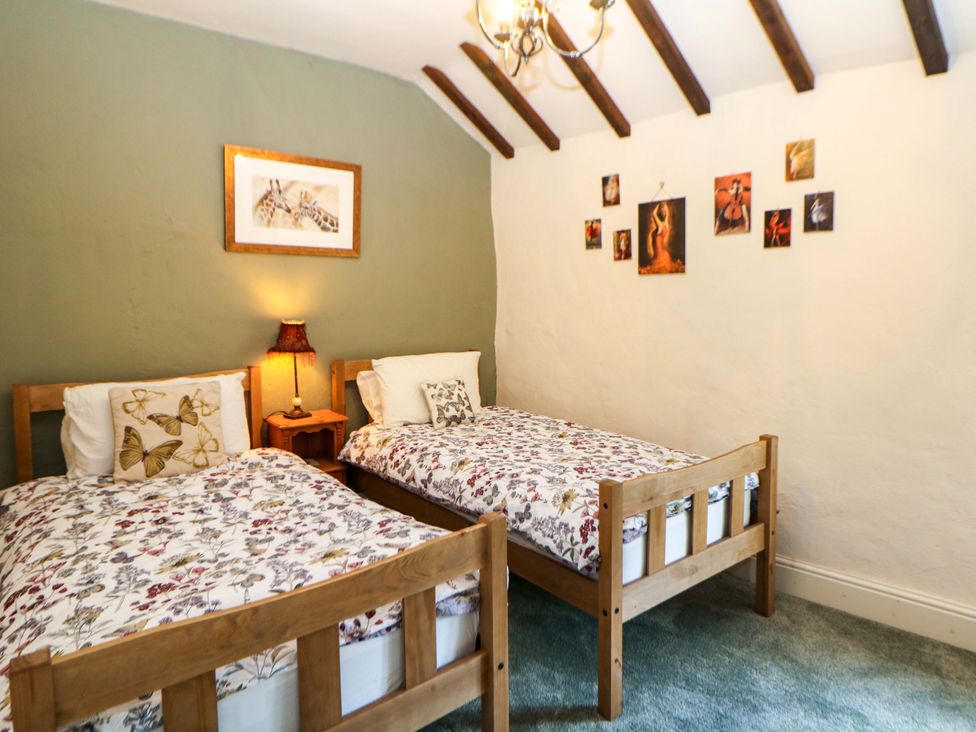 A bedroom with two beds and artwork on the wall at Bargate Cottage Hope Valley