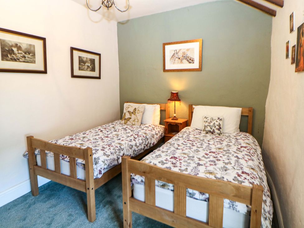 A bedroom with two single beds and nightstand at Bargate Cottage in Hope Valley